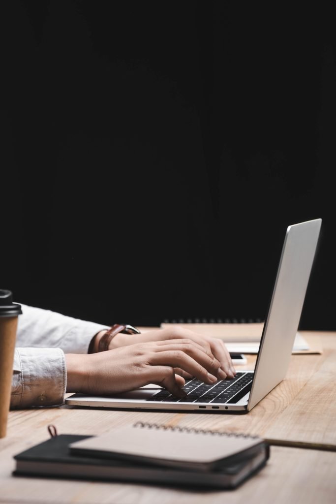 cropped view of seo manager sitting at table and using laptop
